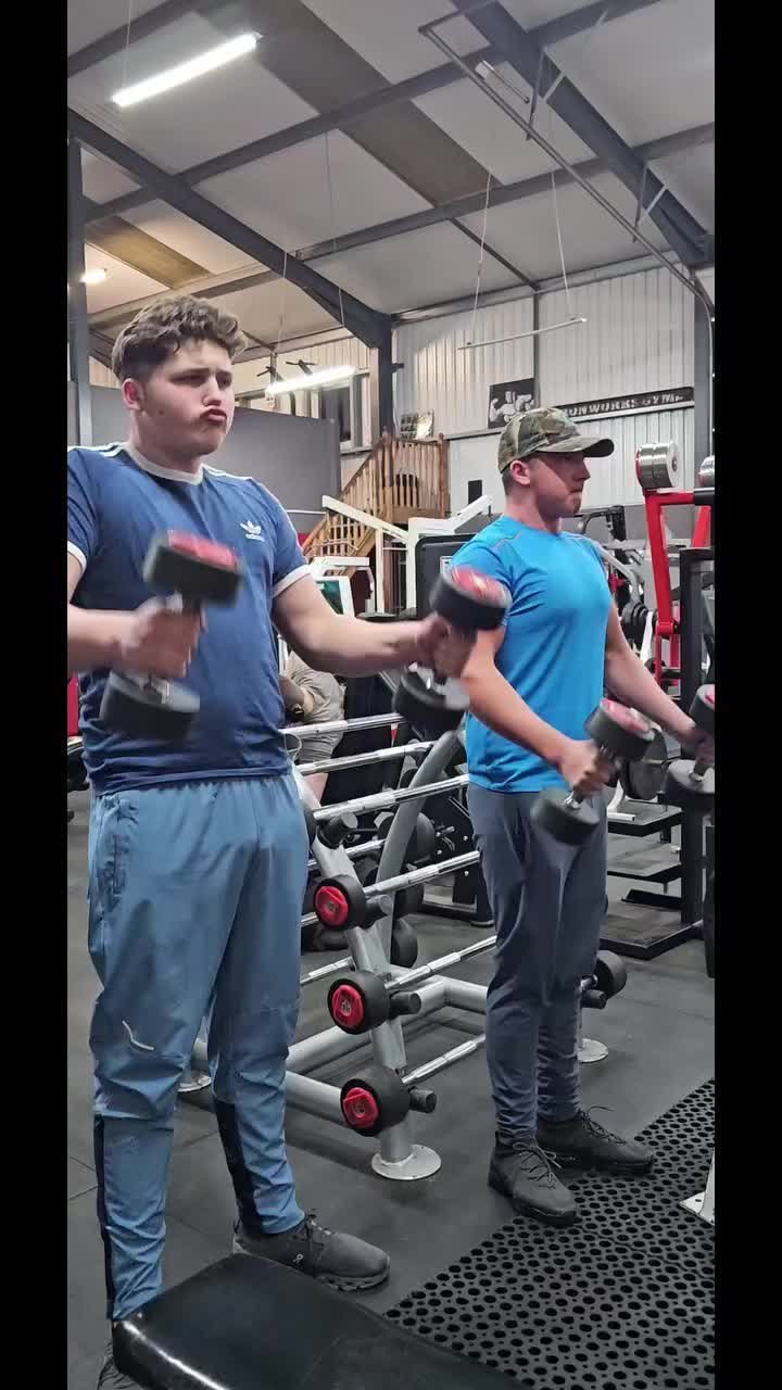 Two members training with dumbbells on the gym floor
